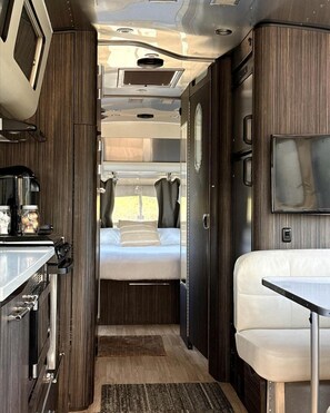 A compact RV interior with a kitchenette, a bed, and a seating area. - Outstanding Airstream Close to Stunning Hiking Trails in Bristol, Texas (Bristol)