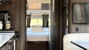 Ein kompaktes Wohnmobil-Interieur mit einer Küchenzeile, einem Bett und einer Sitzecke.