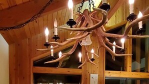 Comedor con mesa de madera, sillas y candelabro con múltiples velas.