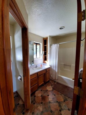 Un baño con ducha, lavamanos y espejo.