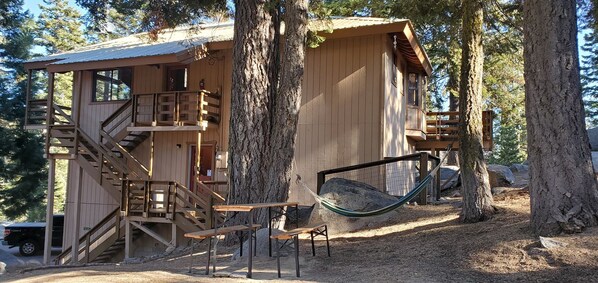 Une cabane en bois dotée d’un balcon, d’un hamac et d’un escalier.