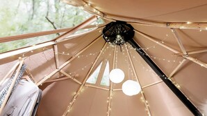 A tent-like structure with a central pole, string lights, and a hanging light fixture. - Enchanting Nordic Tipi for a Montana Glamping Getaway (Bozeman)