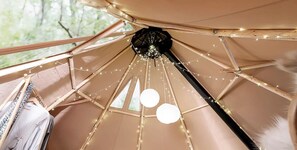Una estructura tipo tienda con un poste central, luces de adorno y una lámpara colgante.