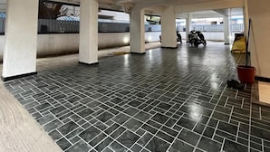 A spacious indoor area with a tiled floor, pillars, and a scooter parked in the distance. - Hotel Sai Residency (Pune)