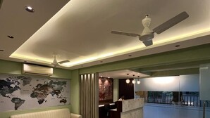 A modern living room with a sofa, coffee table, and a world map on the wall. - Hotel Sai Residency (Pune)