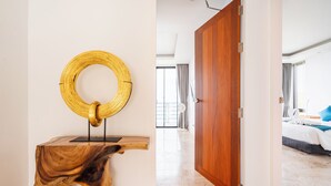 A modern hotel room with a wooden door, a circular wall art piece, and a view of the balcony. - Astoria Villa #2 – 3 Bed Pool Villa in Koh Samui (Chang Wat Surat Thani)