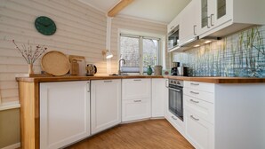 Uma cozinha moderna com armários brancos, bancada de madeira, um relógio e uma janela com persianas.