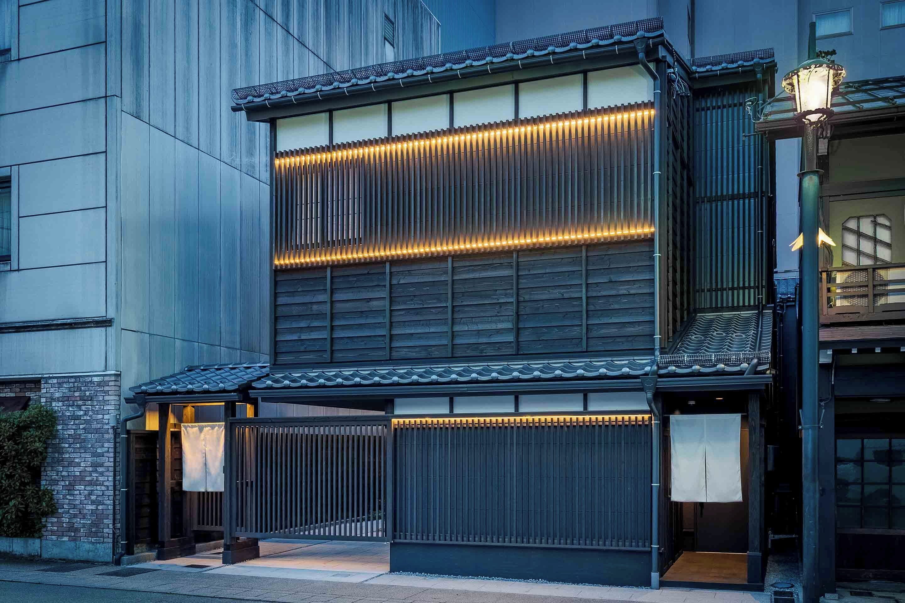 A traditional Japanese building with a modern facade, featuring a wooden entrance with sliding doors and a tiled roof.