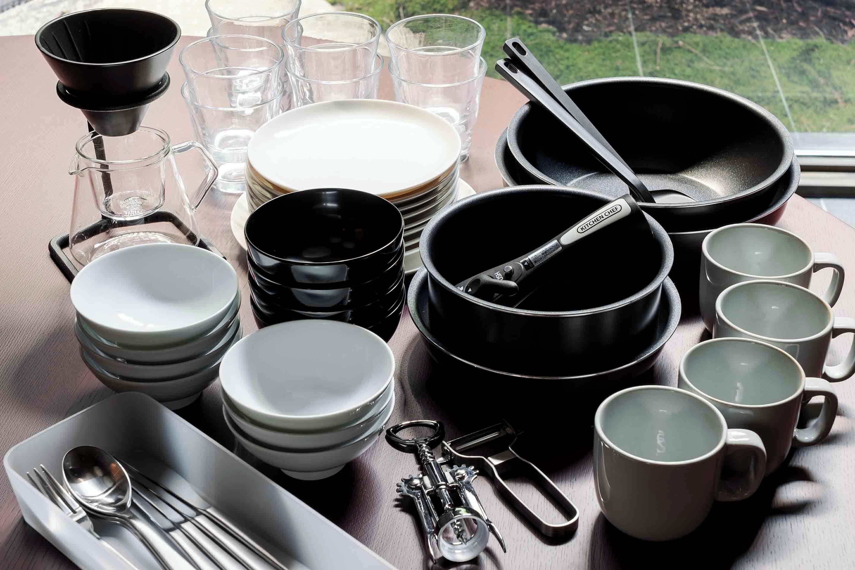 Una mesa ordenada con diversos utensilios de cocina, incluyendo platos, tazones, vasos y cubiertos.