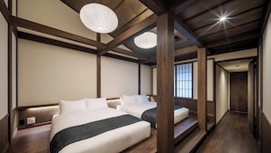 Ein traditioneller japanischer Raum mit zwei Betten, Holzbalken und Schiebetüren.