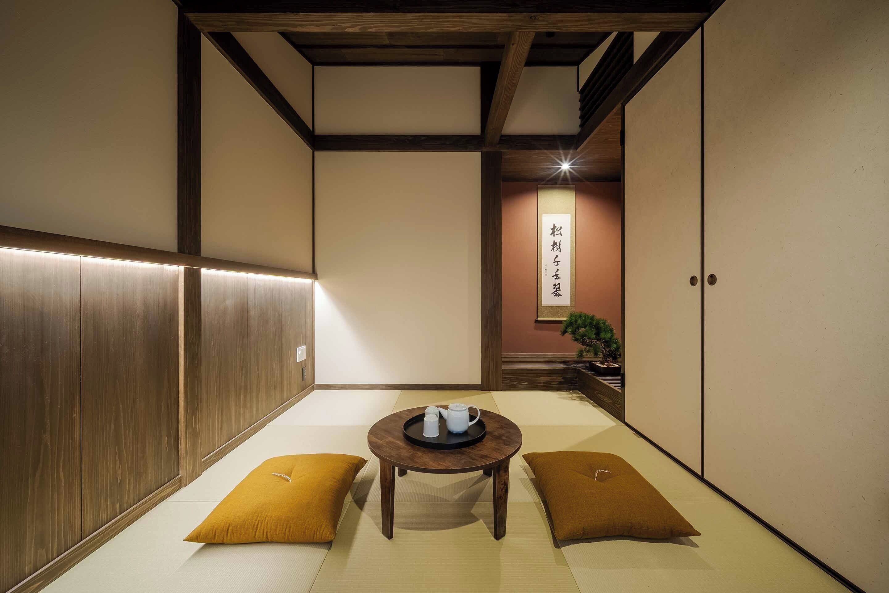 Una tradizionale stanza giapponese con pavimento in tatami, un tavolino con cuscini e porte scorrevoli.