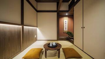 Una tradizionale stanza giapponese con pavimento in tatami, un tavolino con cuscini e porte scorrevoli.