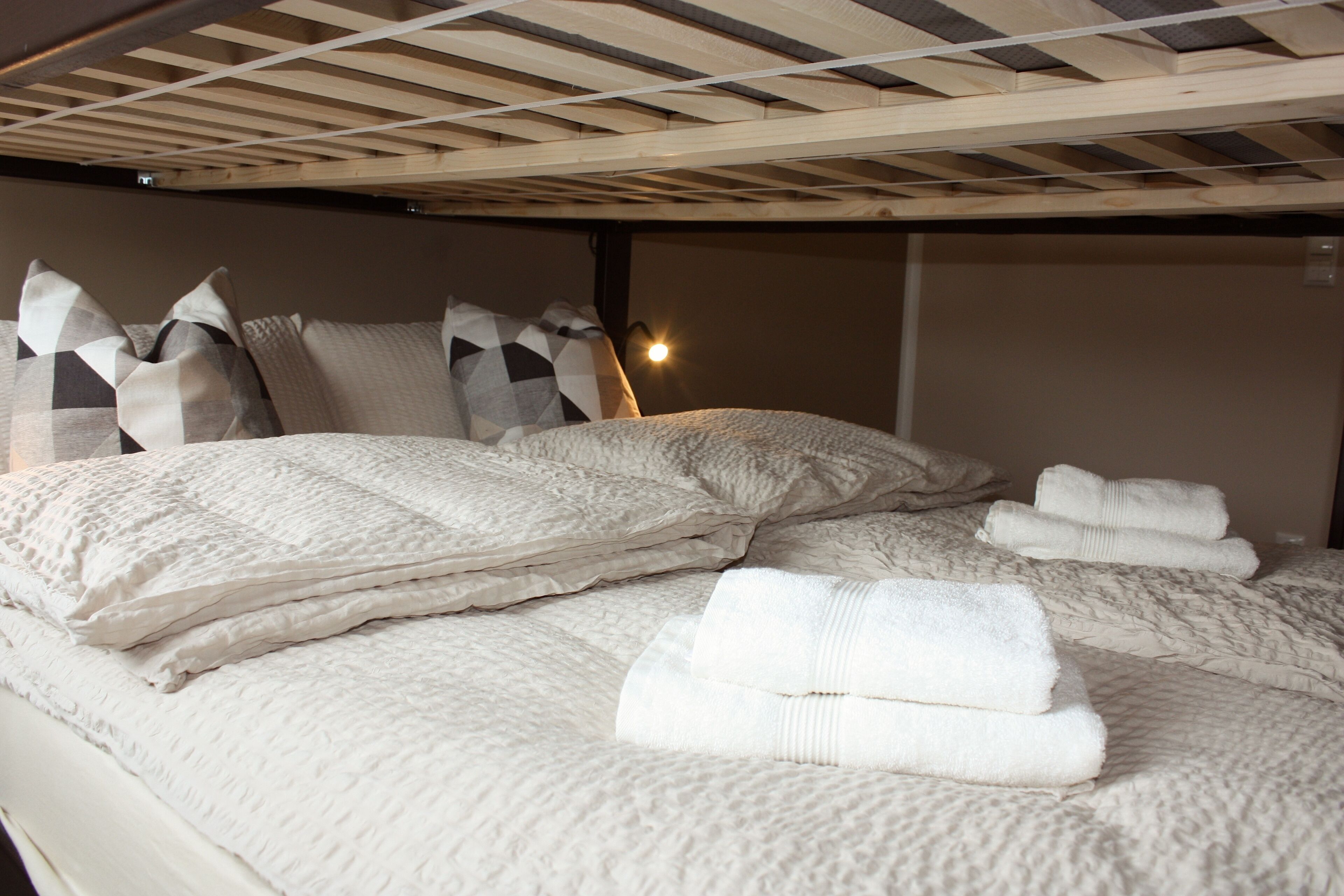 A bunk bed with a wooden ceiling and a white quilted bedspread.