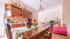 A dining area with a wooden table, chairs, a vase, and a fruit bowl. - Apartment 'La Casa Dei Limoni' with Mountain View and Private Terrace (Gaggi)