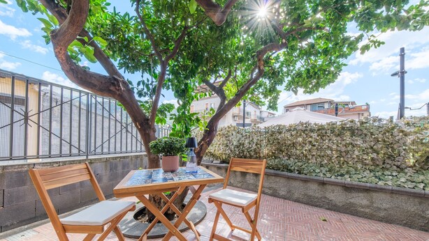 An outdoor patio with a table and chairs, a potted plant, and a view of a residential area. - Apartment 'La Casa Dei Limoni' with Mountain View and Private Terrace (Gaggi)