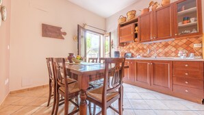 A kitchen with wooden cabinets, a tiled floor, and a dining table with chairs. - Apartment 'La Casa Dei Limoni' with Mountain View and Private Terrace (Gaggi)