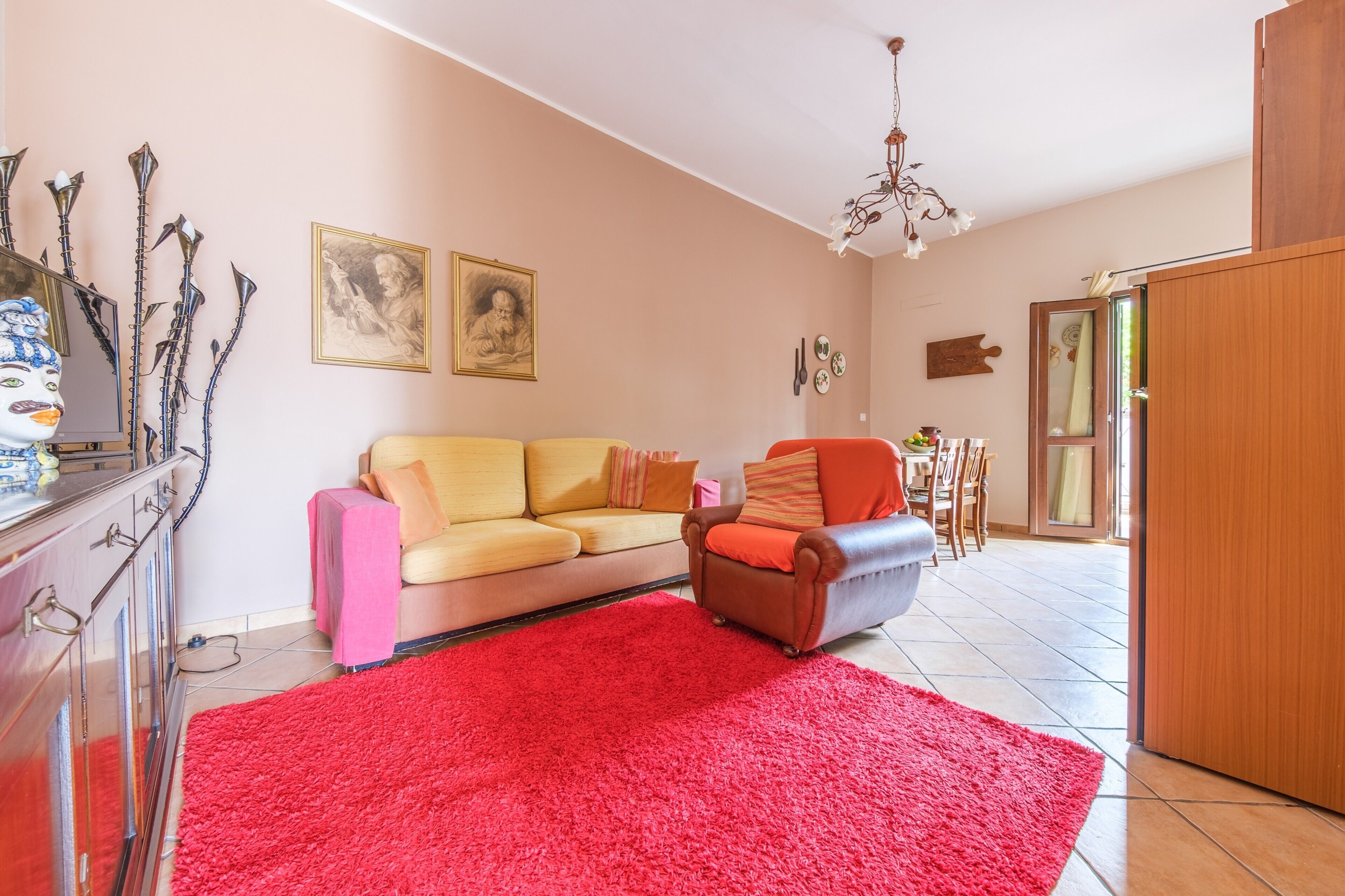 Un salon avec un canapé, un fauteuil, un tapis rouge et un meuble en bois.