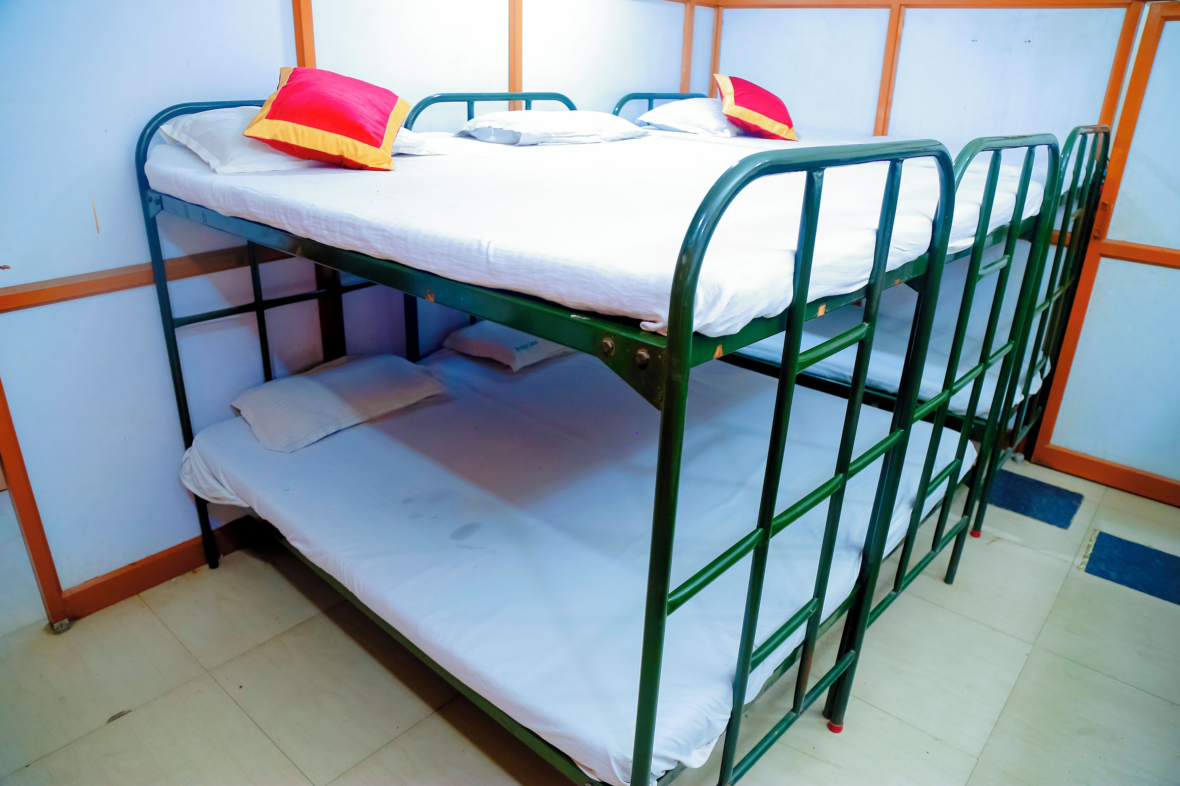 A bunk bed with a mattress and pillows, a lower bunk with a pillow, and a tiled floor.