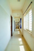 A long, narrow hallway with a tiled floor, a ceiling fan, and a window with bars.