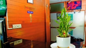Un espace d’accueil comprenant un comptoir de réception, un panneau d’identification, un téléviseur fixé au mur et une plante en pot.