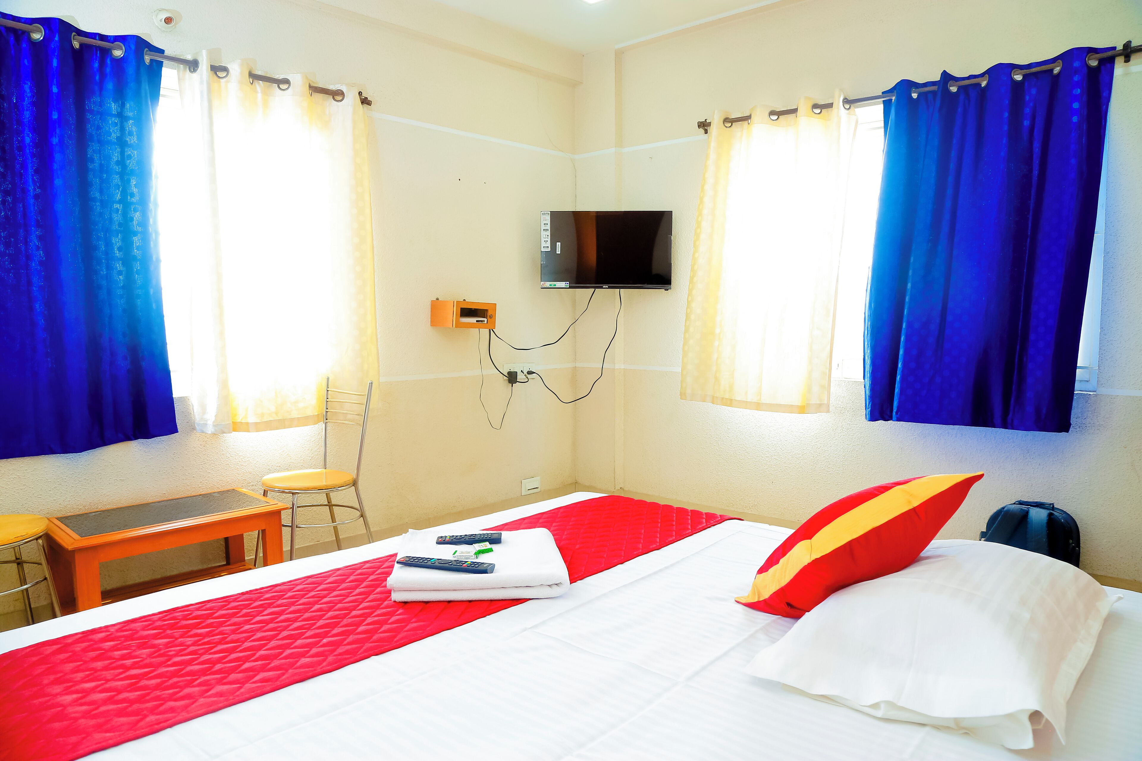 A hotel room with a bed, a TV mounted on the wall, a desk, and a chair.