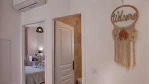 A hallway with a bed, a door, and a welcome sign. - Villa Sandrine (Calvi)