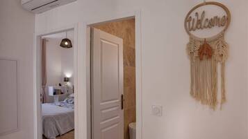 A hallway with a bed, a door, and a welcome sign.