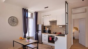 A compact kitchen with a dining area, a clock, and a small island. - Villa Sandrine (Calvi)