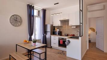 A compact kitchen with a dining area, a clock, and a small island.