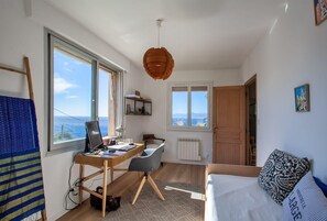 Un dormitorio compacto con escritorio, cama y vista al mar.