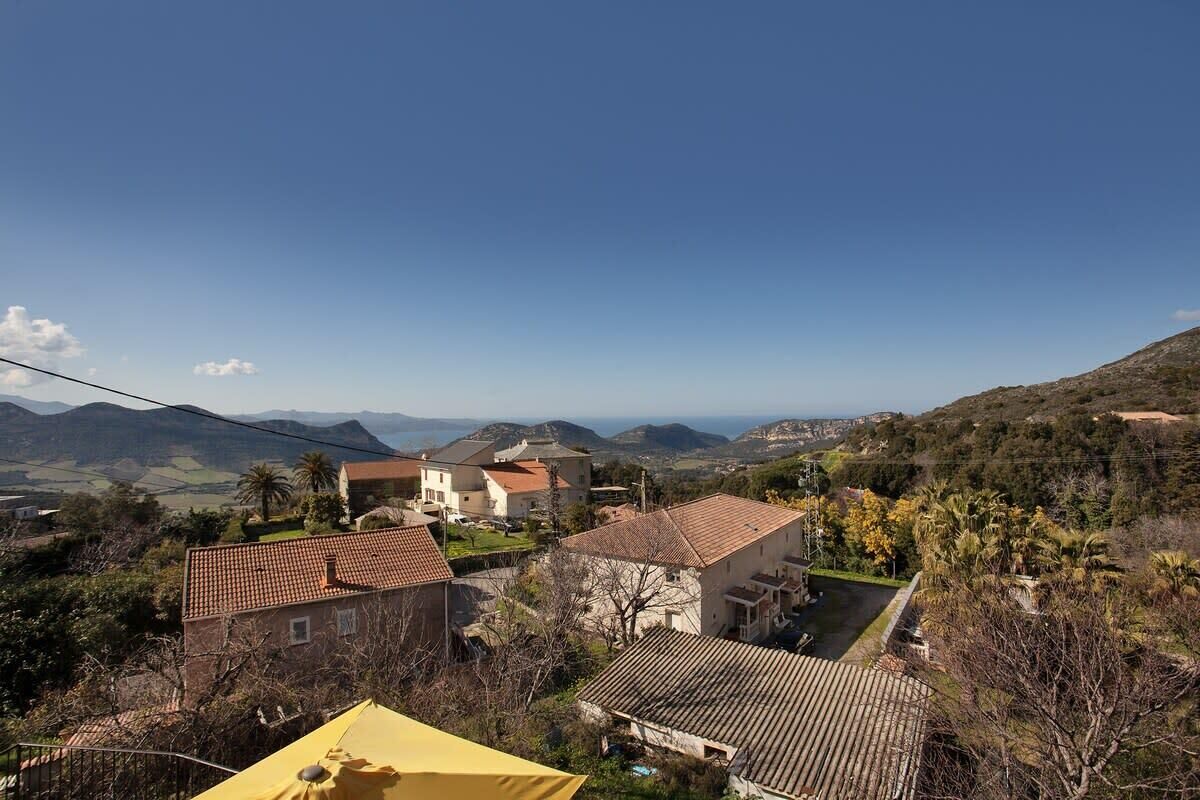A residential area with houses, a yellow umbrella, and a mountainous backdrop.
