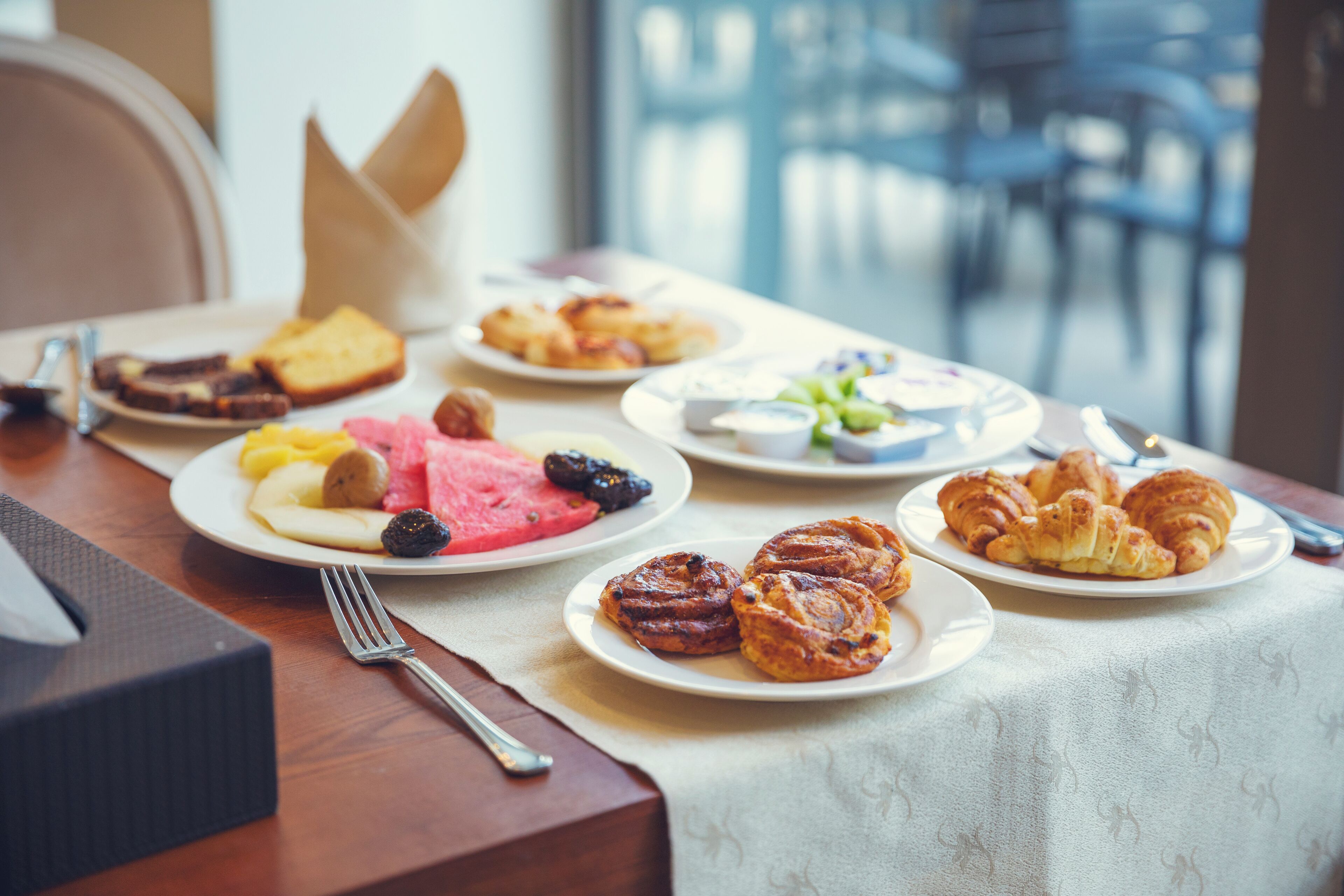 A breakfast table with various pastries, fruits, and bread.