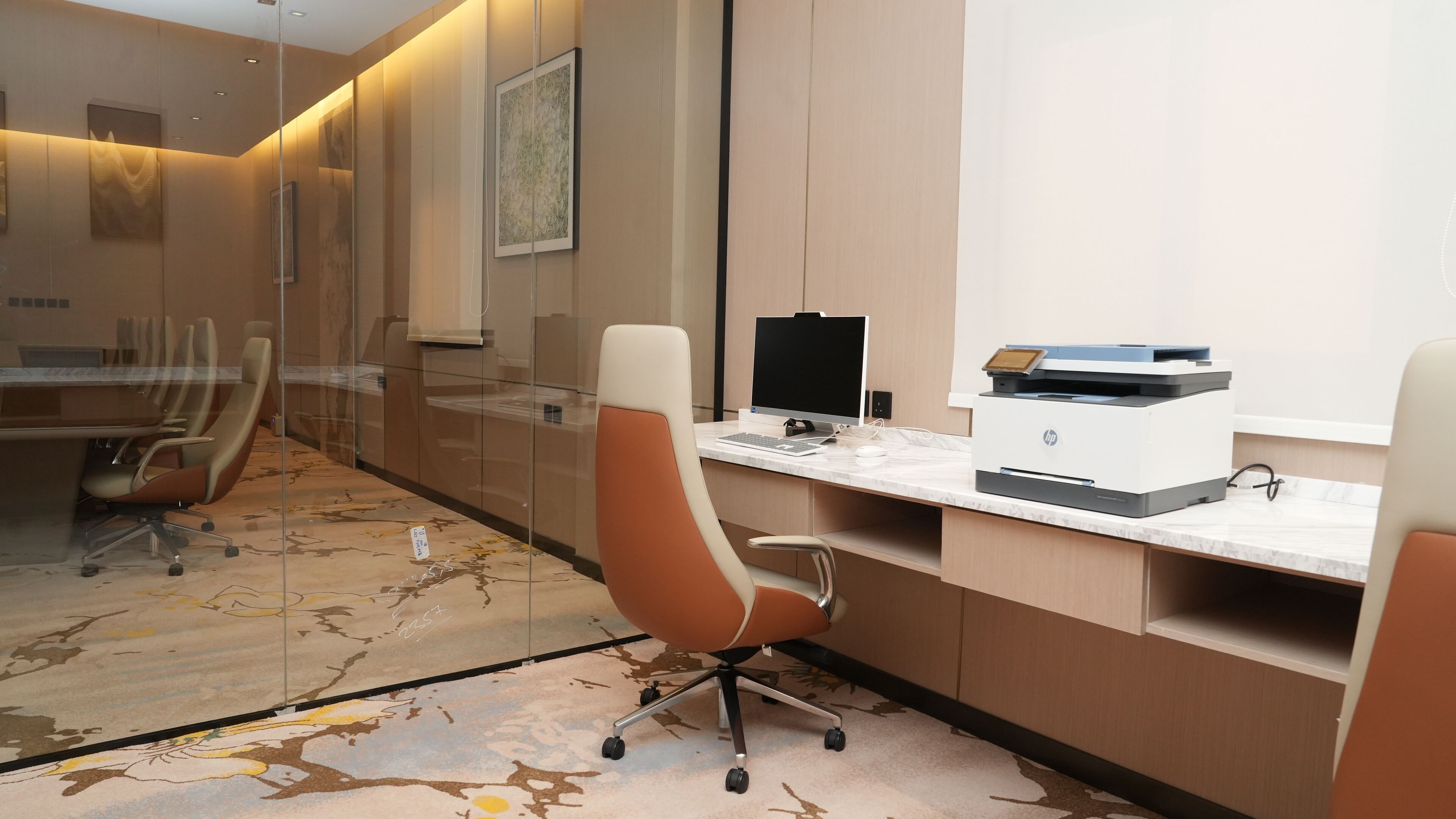 Un espacio de oficina moderno con una larga mesa de conferencias, sillas ergonómicas, un ordenador de escritorio e impresora HP.