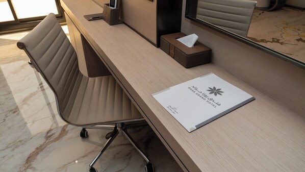 A hotel desk with a chair, a tissue box, and a welcome card. - Rosa Grand Hotel Granada (Riyadh)