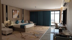 Ett modernt hotellrum med en stor säng, ett skrivbord, en stol, en soffa och utsikt över omgivningarna.