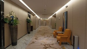 En hotellkorridor med ett marmorgolv, krukväxter och sittgrupper.