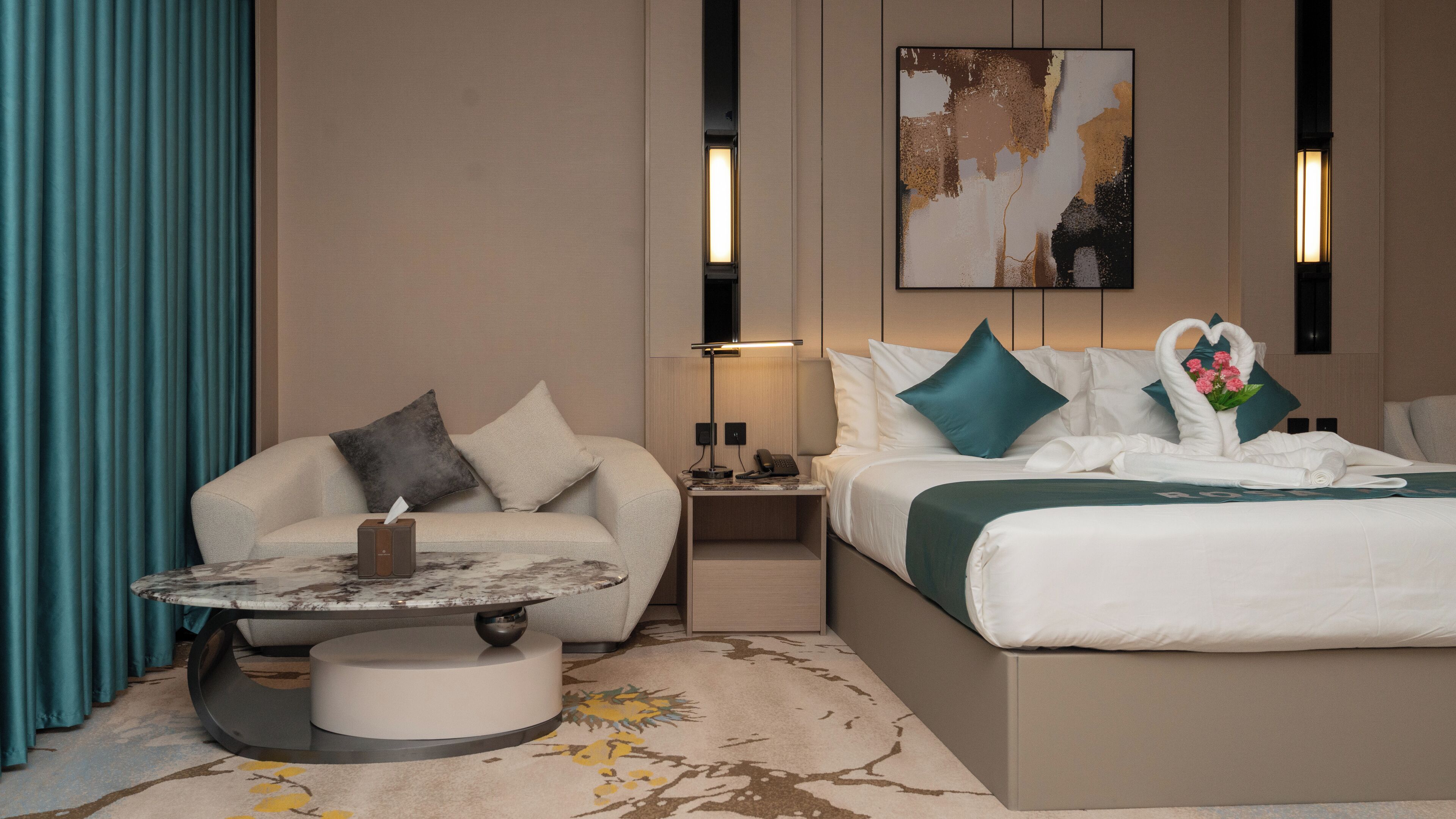 Une chambre d’hôtel avec un lit, un canapé, une table de chevet, une lampe et un tableau au mur.