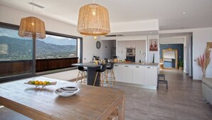 A modern kitchen with a large island, bar stools, and a view of the mountains through the window.