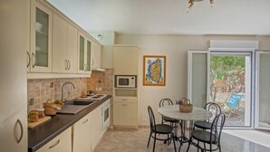 A compact kitchen with a dining area, a microwave, and a view of the outdoors. - Casa Le Sureau (Pino)