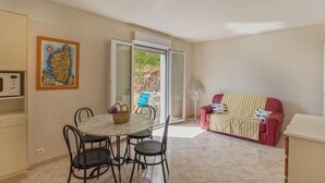 A room with a dining table, chairs, a red sofa, and a fan. - Casa Le Sureau (Pino)