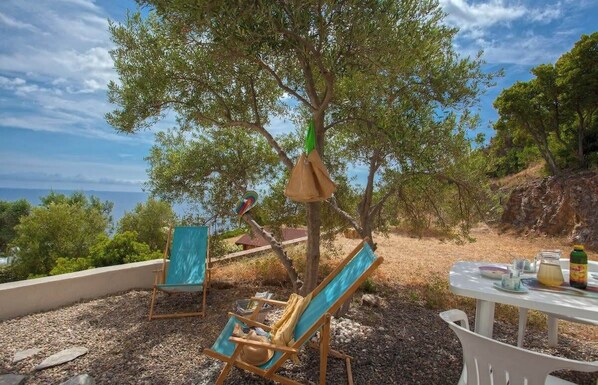 Una terraza con dos sillones, una mesa con una bebida y vista al mar.