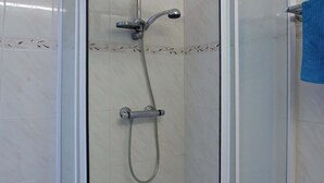 A glass-enclosed shower area with a handheld showerhead and a fixed showerhead, both mounted on a wall. - Casa Le Sureau (Pino)