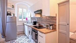 A compact kitchen with a washing machine, a coffee maker, and a built-in stove. - Casa Rione (Omessa)