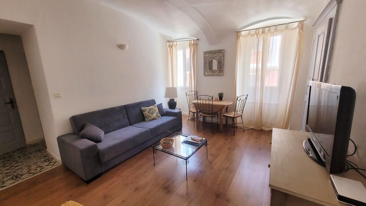 A living room with a sofa, a coffee table, a TV, and a dining area with chairs and a table.