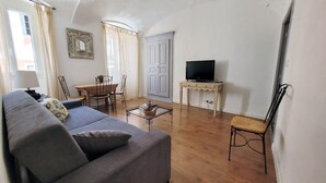 A living room with a sofa, a TV on a stand, a dining table with chairs, and a wardrobe. - Casa Rione (Omessa)
