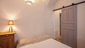 A bedroom with a bed, a nightstand, a lamp, and a sliding door. - Casa Rione (Omessa)
