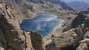 A mountainous landscape with a lake surrounded by rocky terrain. - Casa Rione (Omessa)