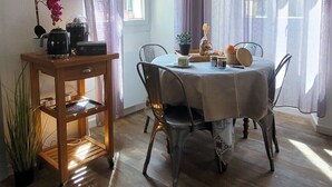 A dining area with a round table, chairs, a pendant light, a wooden side table, and a potted plant. - Casa Torra. (Omessa)