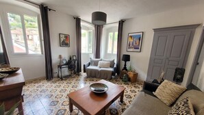 A living room with a patterned floor, a sofa, a coffee table, and a television. - Casa Torra. (Omessa)