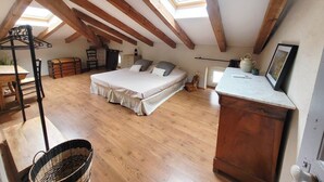 A bedroom with a loft-style ceiling, wooden beams, a bed, a desk, a chair, a chest of drawers, and a window. - Casa Torra. (Omessa)